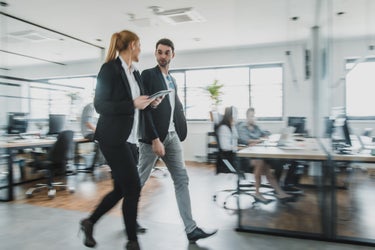 tva personer som gar och pratar i kontorslandskap
