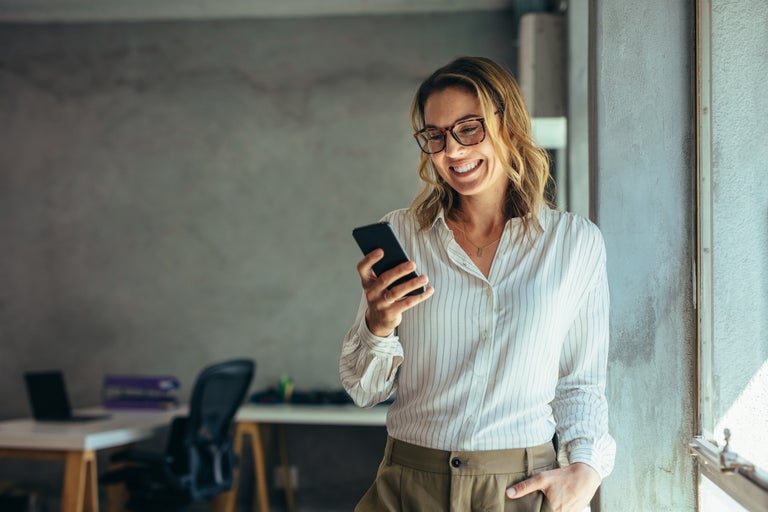 kvinna i motesrum ler in i mobiltelefon