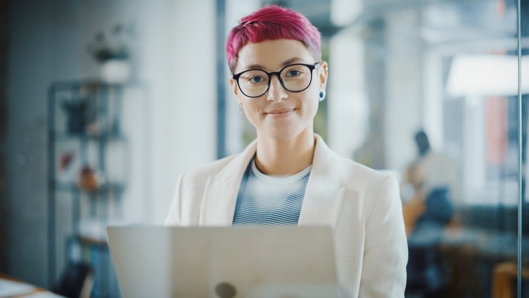 Foto på kvinna med rött hår och kavaj framför en dator.jpeg