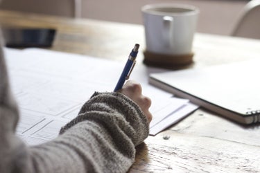 hand skriver pa papper pa ett bord
